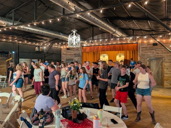 Student travel group taking line dancing lessons under string lights at Enchanted Springs Ranch